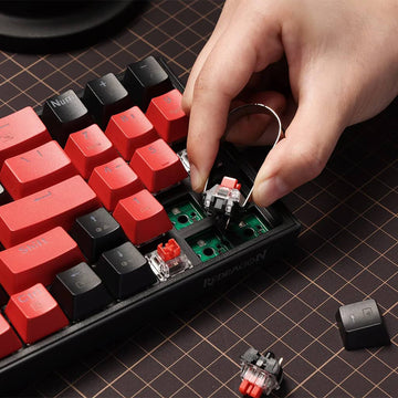 Close-up of a Redragon Pollux Pro K628 RGB gaming keyboard with red and black keycaps and a keycap puller
